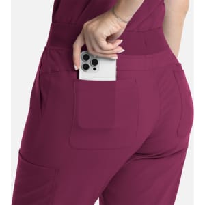 A pair of burgundy flare leg pants with a full elastic band and a phone displayed in the back pocket.
