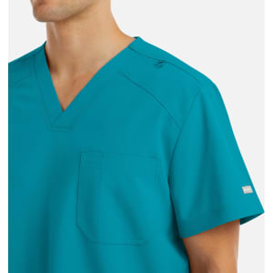 A bright teal men's tuckable v-neck top with a pocket and branding detail on the arm.