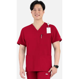 A man wearing a red V-neck top with four pockets, featuring a logo on the sleeve and a tag.