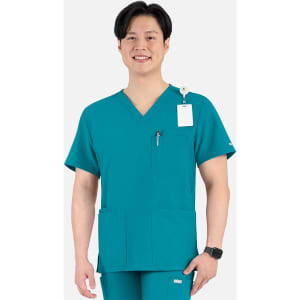 A man wearing a teal V-neck top with four pockets, featuring a logo on the sleeve.