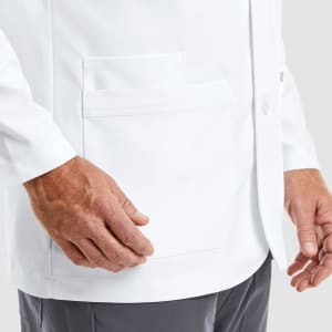 A men's lab coat in white featuring multiple pockets and a button closure, shown on a model's upper body.
