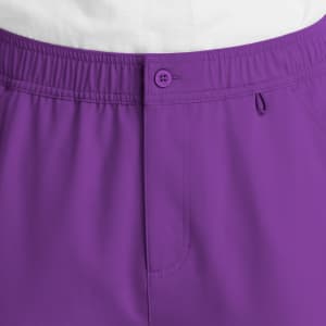A close-up of purple cargo pants featuring a fly front, button closure, and elastic waistband. It has a logo on the waistband.