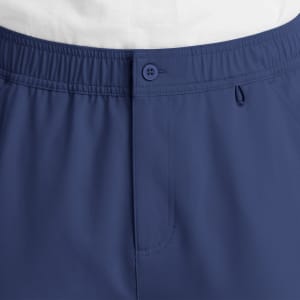 A close-up of navy blue cargo pants featuring a fly front, button closure, and elastic waistband.