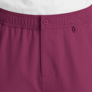 A close-up of men's cargo pants in a deep burgundy colour with a fly front and button detail.
