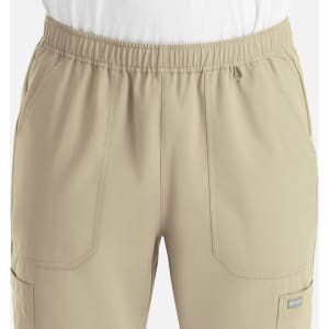 A pair of beige jogger pants featuring a full elastic waist and multiple pockets. The design includes a logo.