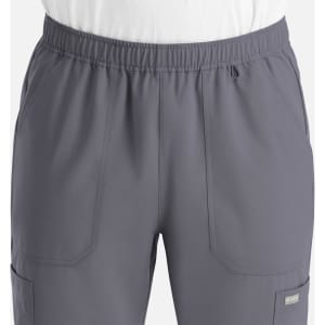 A full elastic jogger in grey featuring multiple pockets and an elastic waistband. The product has a logo.