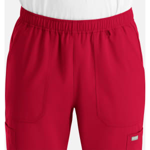 A red pair of full elastic jogger pants with pockets, featuring a waistband and a branding logo.