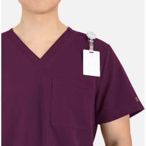 A burgundy V-neck top featuring contrast piping and a pocket, with a badge holder on the shoulder.