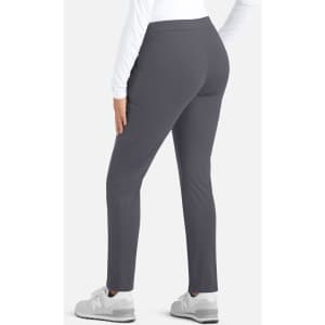 A woman wearing grey mid-rise tapered pants from the back, paired with a white long-sleeve top and grey sneakers.