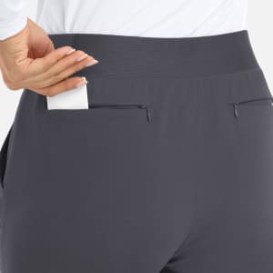 A pair of grey mid-rise joggers with a waistband and two back pockets, one of which has a white card tucked in.