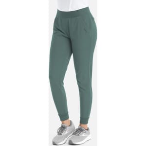 A pair of mid-rise joggers in a green colour, featuring an elastic waistband and cuffs. The model is wearing grey sneakers.