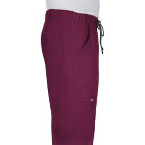 A side view of maroon pants with multiple pockets and an elastic waistband, featuring a logo on the leg.