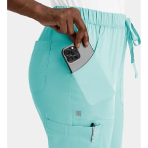 A pair of turquoise cargo pants with elastic waistband, featuring side pockets and a phone being placed in one pocket.