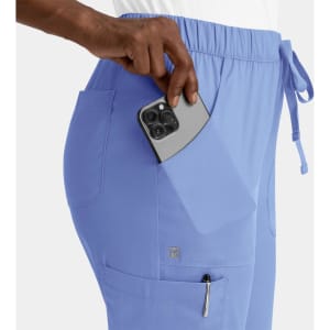 A pair of light blue women's cargo pants with a full elastic waistband, featuring side pockets and a phone being placed in one.