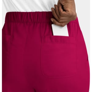 A pair of women's cargo pants in fuchsia with a full elastic waistband and a pocket holding a smartphone.