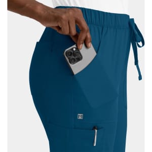 A pair of teal cargo pants with a full elastic waistband and pockets, featuring a hand placing a phone in one pocket.