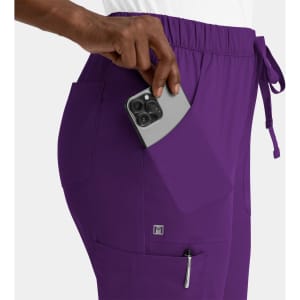 A pair of purple cargo pants featuring a full elastic waistband and pockets, with a smartphone being placed in one pocket.