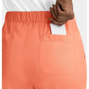 A pair of peach cargo pants with a full elastic waistband and a smartphone partially visible in the pocket.