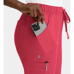 A pink cargo pant with a full elastic waistband, featuring a hand placing a phone into the side pocket.