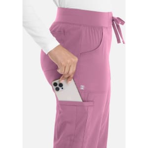 A pair of women's joggers in pink, featuring side pockets and a drawstring waist, with a phone being placed in one pocket.