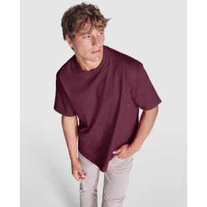 A maroon oversized t-shirt on a model, featuring a simple design and a branding logo.
