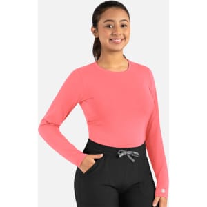 A pink long-sleeved tee is displayed on a model, paired with black pants. The tee features a small logo.