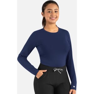A navy long-sleeve underscrub tee being worn with black pants, featuring a logo on the sleeve.
