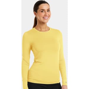 A yellow long-sleeve underscrub tee with a fitted design. The model is smiling and the product includes branding.