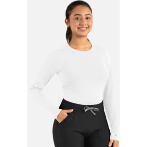 A long-sleeve underscrub tee in white, worn with black pants, featuring a logo on the sleeve.