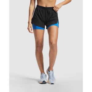 Black running shorts featuring blue under-shorts, with an elastic waistband and side panels. The model is wearing running shoes.