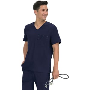 A man wearing a navy scrub top with a pocket, holding a stethoscope, smiling at the camera.