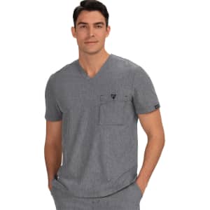 A grey V-neck scrub top featuring a chest pocket and a logo. The model is casually posing with hands in pockets.