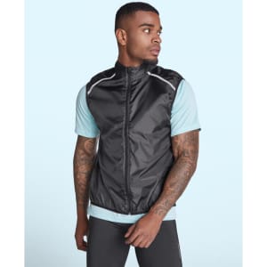 A man wearing a black ultra-light windbreaker vest over a light blue shirt, featuring reflective details and a logo.
