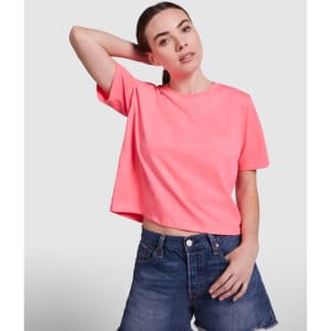 A cropped top in bright pink, featuring short sleeves and a loose fit, paired with denim shorts.