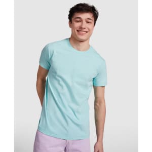 A light blue T-shirt featuring a classic crew neckline, displayed by a smiling young man. The shirt has a logo.
