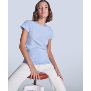 A light blue women's t-shirt with a fitted design, displayed on a seated model against a neutral background.