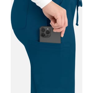 A hand placing a phone into the pocket of teal women's cargo pants with an elastic waistband.