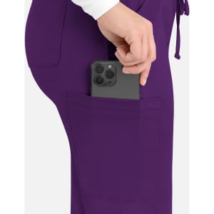 A close-up of purple cargo pants with a phone being placed in the side pocket.
