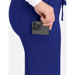 A woman's hand placing a smartphone into the pocket of blue cargo pants. The pants feature a sleek design with a logo.