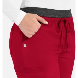 A close-up of red cargo pants featuring a grey waistband and pockets, with a small logo on the side.