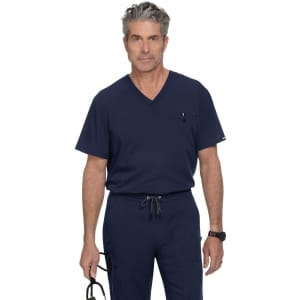 A navy blue scrub top featuring a V-neck design and a chest pocket, modelled by a man holding eyewear.