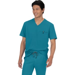 A teal scrubs top featuring a v-neck design and a pocket, modelled by a smiling person.