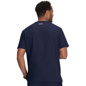 A man wearing a navy blue scrub top, viewed from the back. The top features a logo on the back.