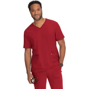 A man in a red scrub set stands smiling, holding a medical tool, with pockets on both the top and pants.