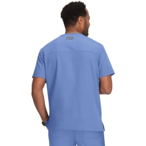 A medical scrub top in light blue with a back detail and a logo on the neckline, worn by a person from behind.