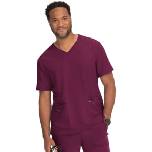 A man wearing a burgundy medical scrub top with a V-neck and two front pockets, featuring a logo.