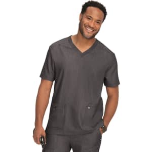 A man wearing a grey scrub top with a V-neck design and two front pockets, smiling confidently.
