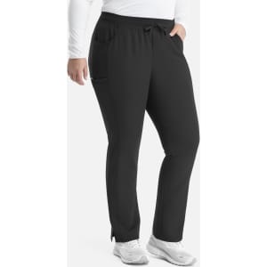 Black tapered pants with a waistband and pockets, featuring a logo. Model wearing a long-sleeved white top.