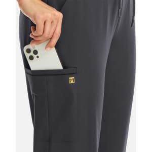 A navy jogger featuring a metallic detail and a pocket holding a smartphone, with a logo visible on the side.