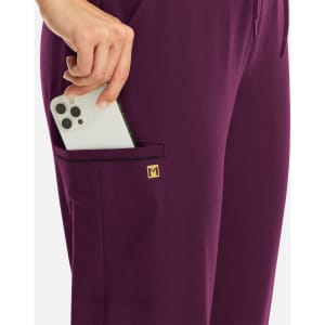 A pair of women's joggers in deep purple with a metallic detail, featuring a pocket holding a smartphone.